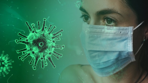 Eine weibliche Person, welche eine medizinische Maske trägt befindet sich rechts im Bildhintergrund. Vorne links ist ein Corona-Virus zu sehen.